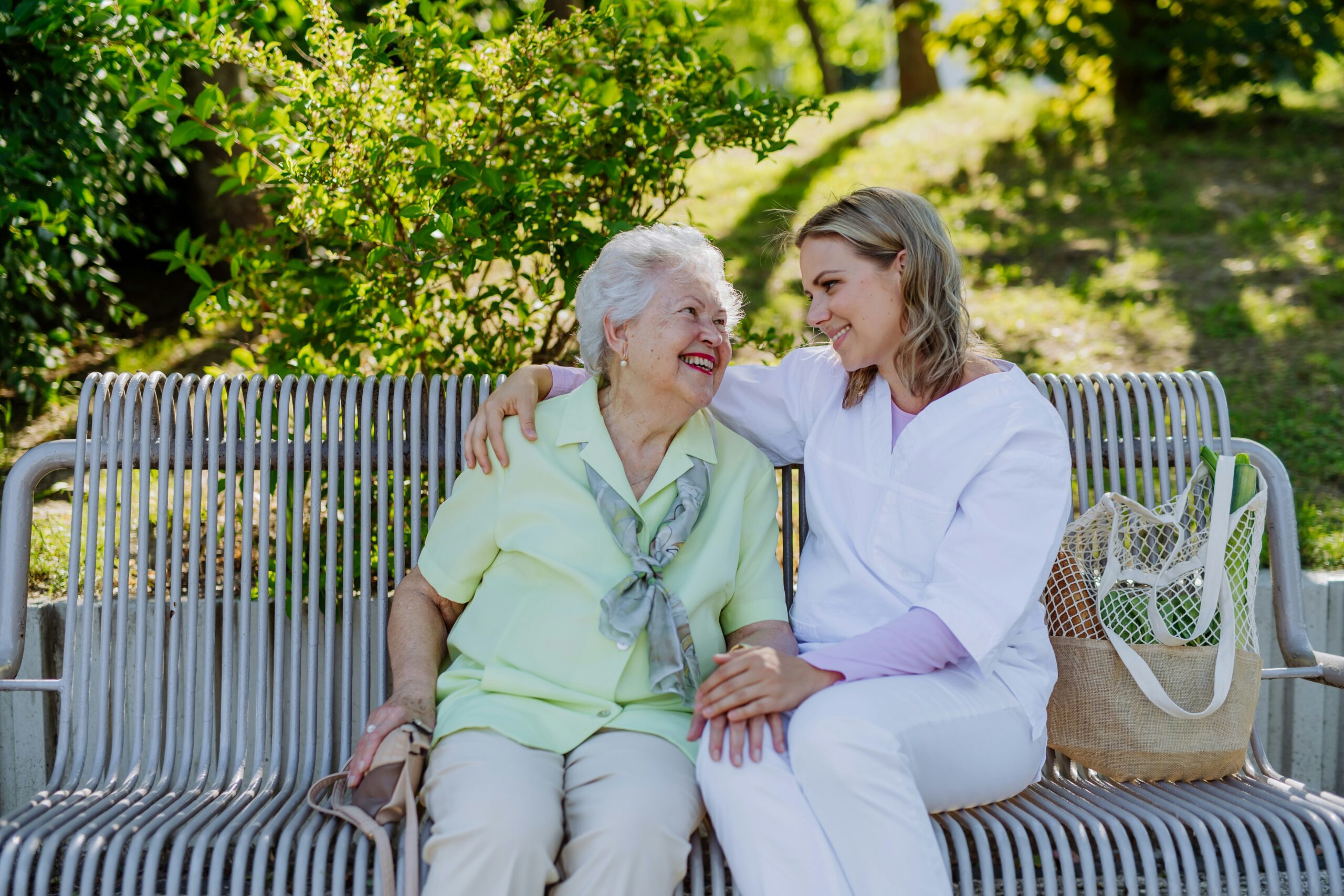 elderly woman sitting with middle aged woman on a bench elderly woman sitting with middle aged woman on a bench